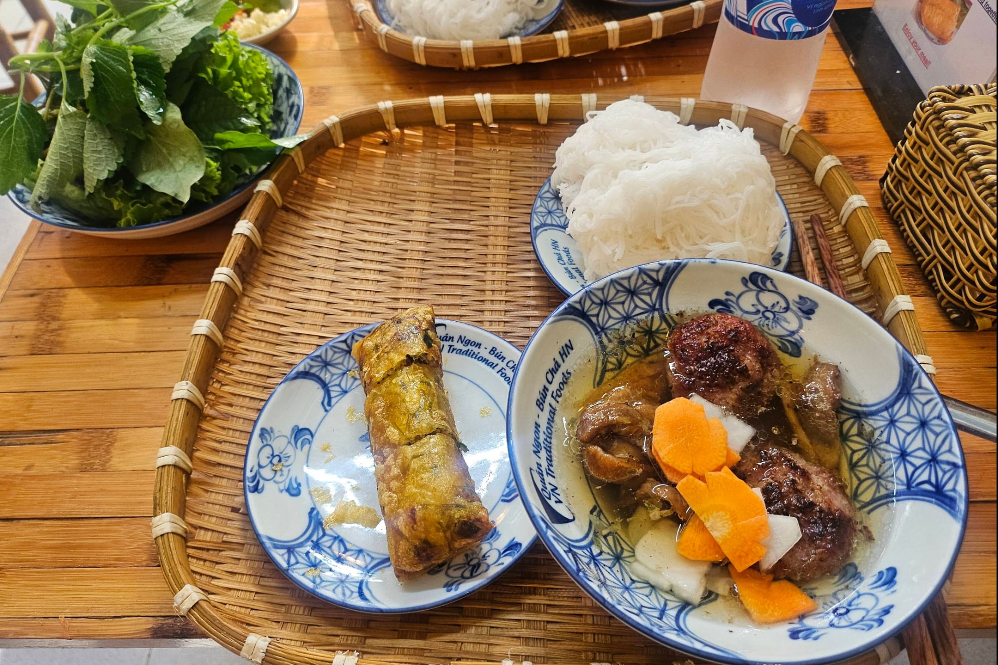 The special bun cha set includes grilled pork served in a sweet and tangy fish sauce, accompanied by a crispy fried spring roll 